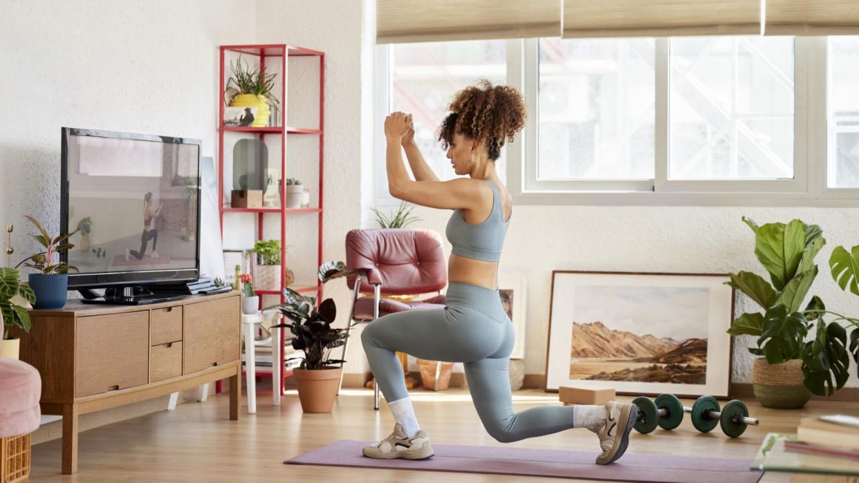  Woman performs lunges on a yoga mat at home. 