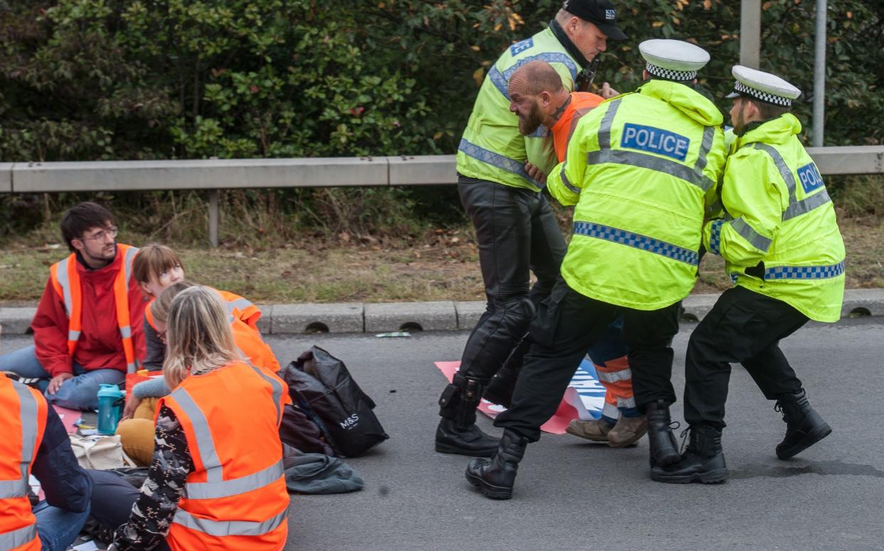 Police restrain an angry member of the public during Wednesday's motorway protests, with the sit-in allowed to continue undisturbed