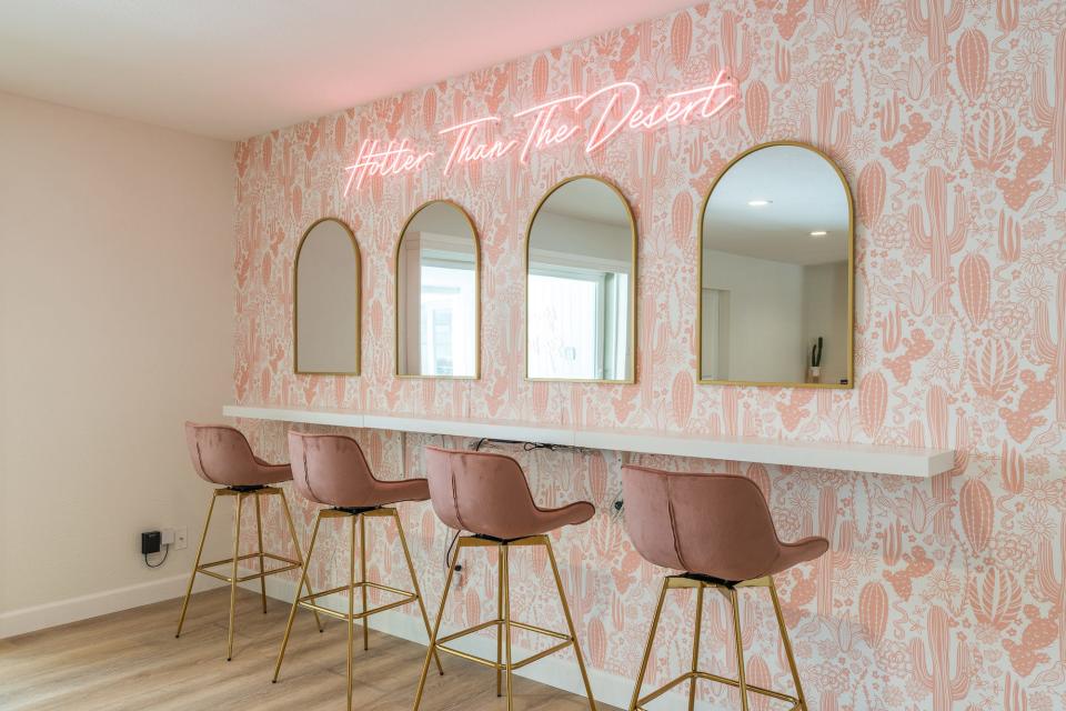 A pink wall with mirrors and chairs.