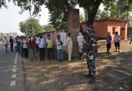 A security officer wearing a face shield as a protective measure against the coronavirus stands guard as voters stand in a queue at a polling station, during the first phase of state elections at Paliganj, in the eastern Indian state of Bihar, Wednesday, Oct. 28, 2020. With an overall declining coronavirus positive trend, Indian authorities decided to hold the first state legislature election since the outbreak of COVID-19. People began voting Wednesday in the country’s third largest state Bihar with of a population of about 122 million people. (AP Photo/Aftab Alam Siddiqui)