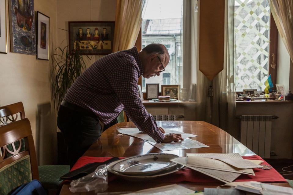 Ukrainian writer Andrey Kurkov, 62, looks at the old maps of Kyiv, one from 1918 and one from 1919, at home in Kyiv, Ukraine on Feb. 23, 2024. A few years ago Kurkov received a box of original documents from 1919 from the Bolshevik militia and secret police, which inspired a series of detective novels that take place in 1919 Kyiv. (Oksana Parafeniuk for The Washington Post via Getty Images)