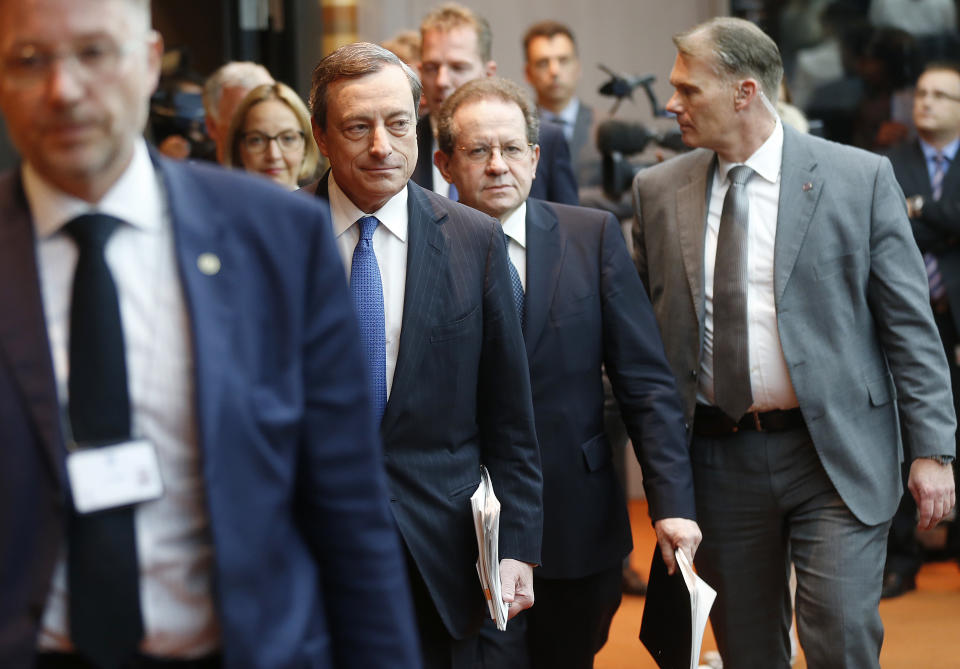 President of European Central Bank, Mario Draghi ,  second left,  is on the way to a news conference in Frankfurt, Germany, Thursday, June 5, 2014,.  The European Central Bank has cut two key interest rates, one of them into negative territory — a highly unusual step that underlines the urgency of its efforts to keep the eurozone economy from sliding into crippling deflation. It reduced its main interest rate, the refinancing rate, from a record low of 0.25 percent to 0.15 percent. More drastically, it also cut the rate it pays on money deposited by banks from zero to minus 0.1 percent, an unprecedented step for the ECB that aims to push banks to lend money rather than hoard it.   (AP Photo/Michael Probst)