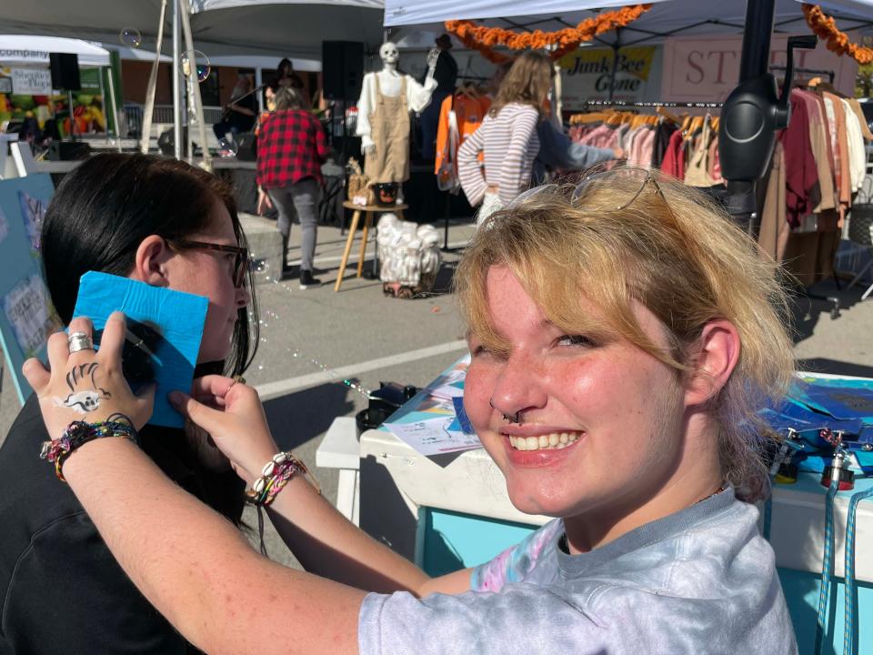 Rebecca Bowman from Planet Fitness is getting a tattoo stencil from Megan Thomas, a popular draw, at the third annual Farragut Harvest Festival at Village Green Shopping Center, Oct. 22, 2023.