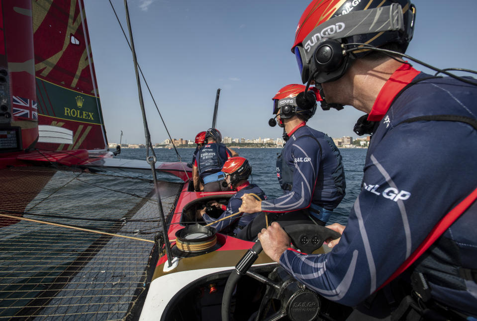 In this handout provided by SailGP, Ben Ainslie, driver of Emirates Great Britain SailGP Team, at the wheel as he sits alongside Iain Jensen, wing trimmer, Luke Parkinson, flight controller, Nick Hutton, grinder, and Matt Gotrel, grinder, during a practice session ahead of the Italy Sail Grand Prix sailing event in Taranto, Italy, Friday, Sept. 22, 2023. (Ricardo Pinto/SailGP via AP)