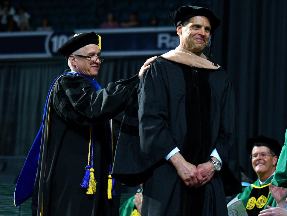 Boston Bruins general manager Donald Sweeney is presented with an honorary doctor of business administration degree by trustee David Hale during Nichols College's commencement Saturday at the DCU Center.