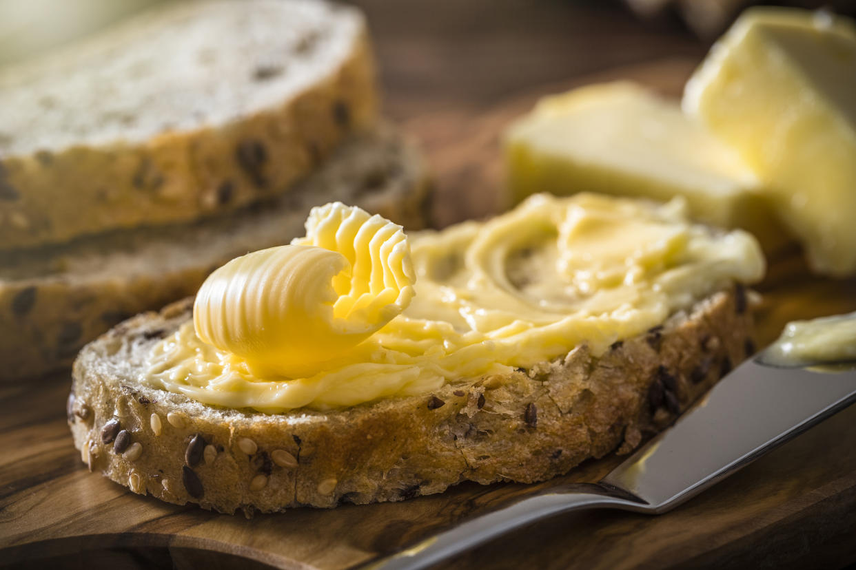 Front view of a slice of bread spread with butter with a butter curl on top