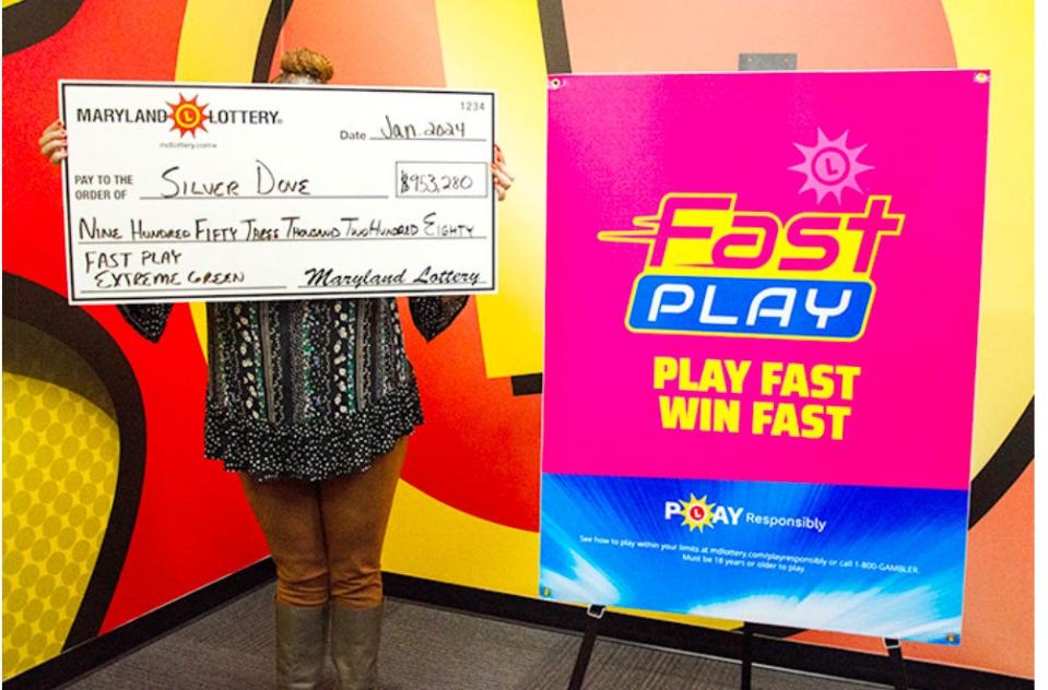 A woman who wants to remain anonymous holds up the check she got after winning a progressive jackpot in the Fast Play Extreme Green game from the Maryland Lottery.