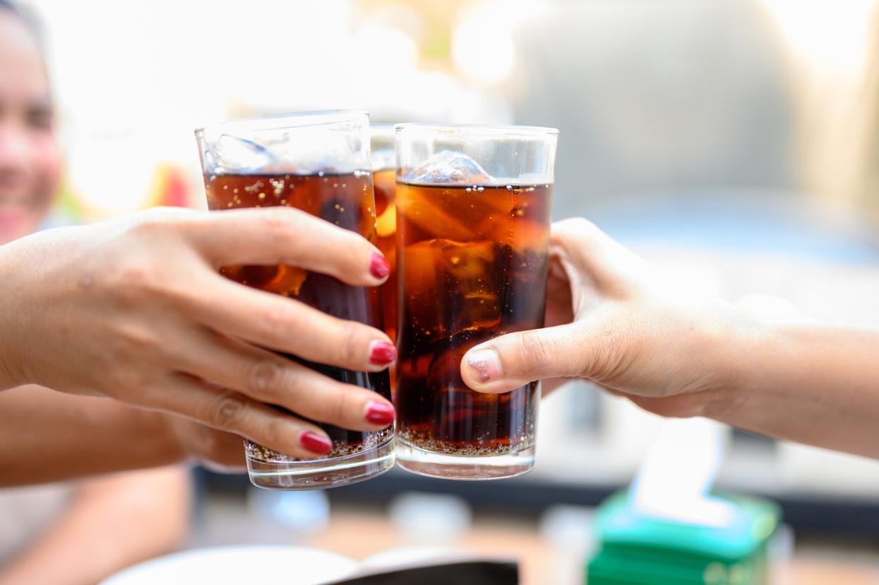 Hands holding glasses of soft drinks made with artificial sweetener. (Getty Images)
