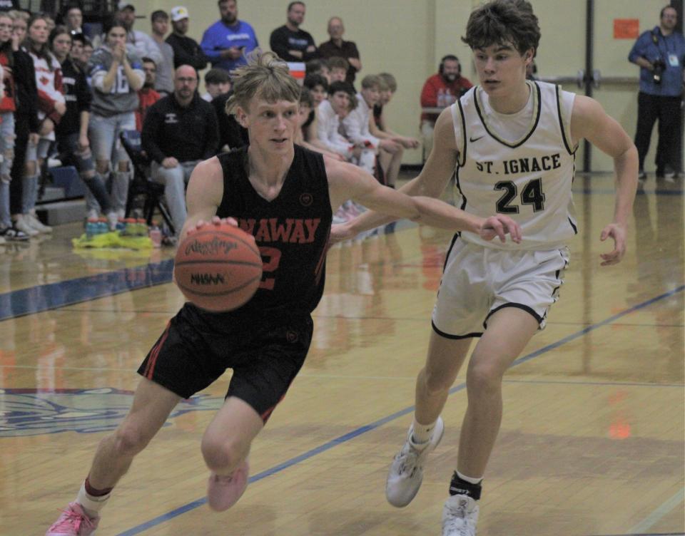 Onaway senior guard Jadin Mix (left) drives past St. Ignace's Caden Lester (24) and heads for the basket during the first half of Tuesday's boys basketball regional semifinal game at Inland Lakes. Mix scored a team-high 38 points in his last game as a Cardinal.