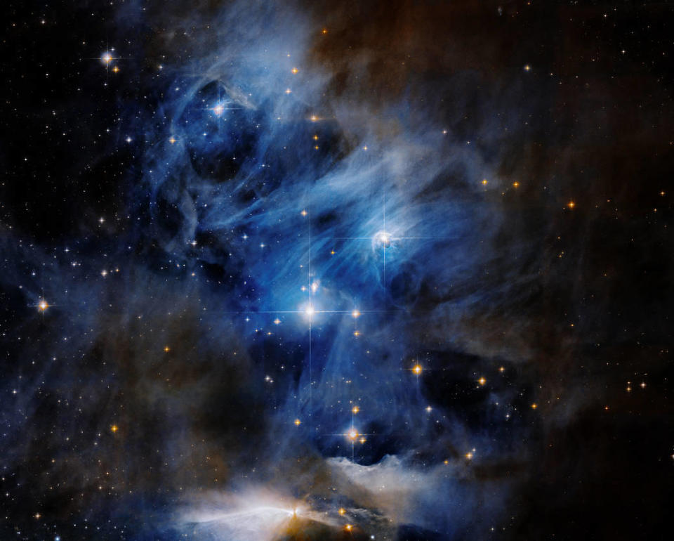 This NASA Hubble Space Telescope image captures one of three segments that comprise a 65-light-year wide star-forming region named the Chamaeleon Cloud Complex. The segment in this Hubble composite image, called Chamaeleon Cloud I, reveals dusty-dark clouds where stars are forming, dazzling reflection nebulae glowing by the light of bright-blue young stars, and radiant knots called Herbig-Haro objects. / Credit: NASA, ESA, K. Luhman and T. Esplin (Pennsylvania State University), et al., and ESO; Processing: Gladys Kober (NASA/Catholic University of America)