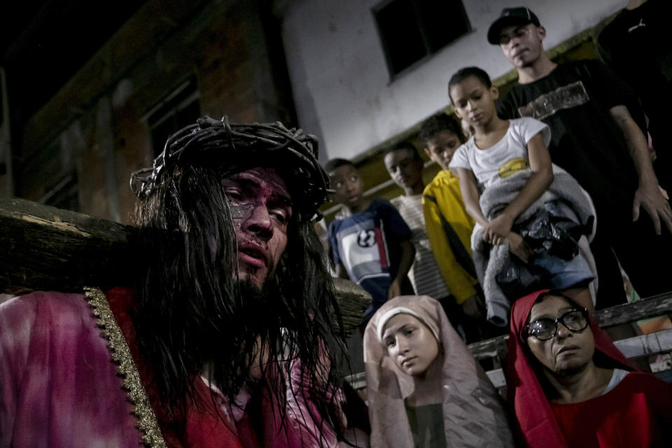 Luiz Henrique (izquierda), que interpreta el papel de Jesucristo, carga con la cruz durante una recreación del Via Crucis dentro de la celebración de la Semana Santa en la favela Complexo do Alemao, en Río de Janeiro, Brasil, el 29 de marzo de 2024. La Semana Santa conmemora los últimos días de la vida de Jesús, según la Biblia, incluyendo su crucifixión el Viernes Santo y su resurrección en el Domingo de Pascua. (AP Foto/Bruna Prado)