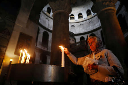 FILE PHOTO: A worshipper lights a candle as she visits the Church of the Holy Sepulchre in Jerusalem's Old City January 22, 2018. REUTERS/Ammar Awad/File Photo