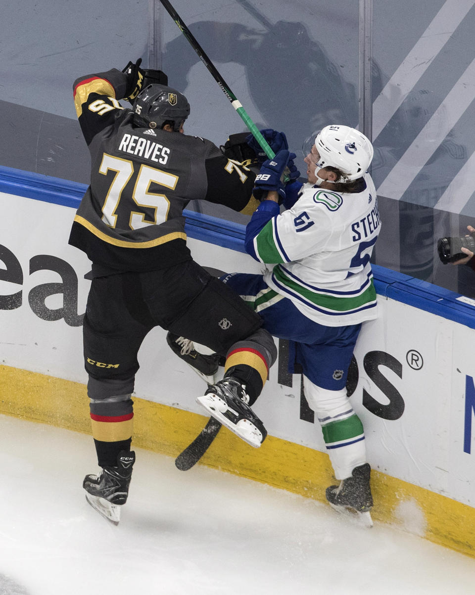 Vegas Golden Knights' Ryan Reaves (75) checks Vancouver Canucks' Troy Stecher (51) during the first period of an NHL Western Conference Stanley Cup playoff game in Edmonton, Alberta, on Tuesday, Aug. 25, 2020. (Jason Franson/The Canadian Press via AP)