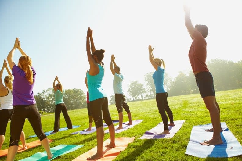 People taking part in outdoor group yoga meditation exercises.