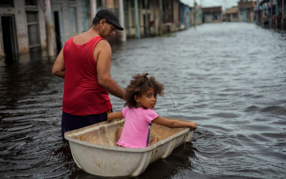 Jesus Hernandez guides his granddaughter Angelina via a container through a street flooded in the passing of Hurricane Helene