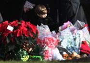 NEWTOWN, CT - DECEMBER 18: A child stands next to a makeshift memorial for Jessica Rekos, 6, following her funeral at the St. Rose of Lima Catholic church on December 18, 2012 in Newtown, Connecticut. Funeral services were held at the church for both Jessica Rekos and James Mattioli, 6, Tuesday, four days after 20 children and six adults were killed at Sandy Hook Elementary School. (Photo by John Moore/Getty Images)