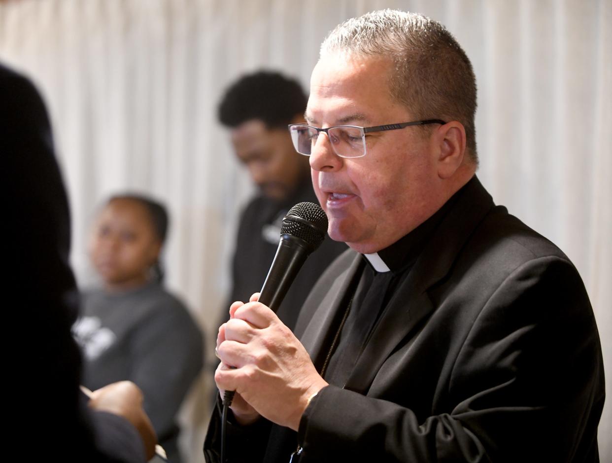 Catholic Diocese of Youngstown Bishop David Bonnar offers a blessing to Ronnie Dykes and Ashya Mathis and their sons Josiah, 14, Jay'On, 12, and Jaiaire, 11, for their new home, which was built through Habitat for Humanity East Central Ohio with help from volunteers from Stark County Catholic churches.