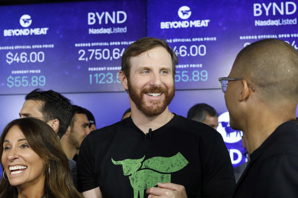 Beyond Meat CEO Ethan Brown, center, watches as his company's stock begins to trade following its IPO at Nasdaq, Thursday, May 2, 2019 in New York. California-based Beyond Meat makes burgers and sausages out of pea protein and other ingredients. (AP Photo/Mark Lennihan).