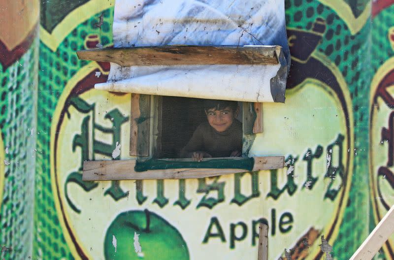 A Syrian refugee boy looks out from a tent window, as Lebanon extends a lockdown to combat the spread of the coronavirus disease (COVID-19) at a Syrian refugee camp in the Bekaa valley