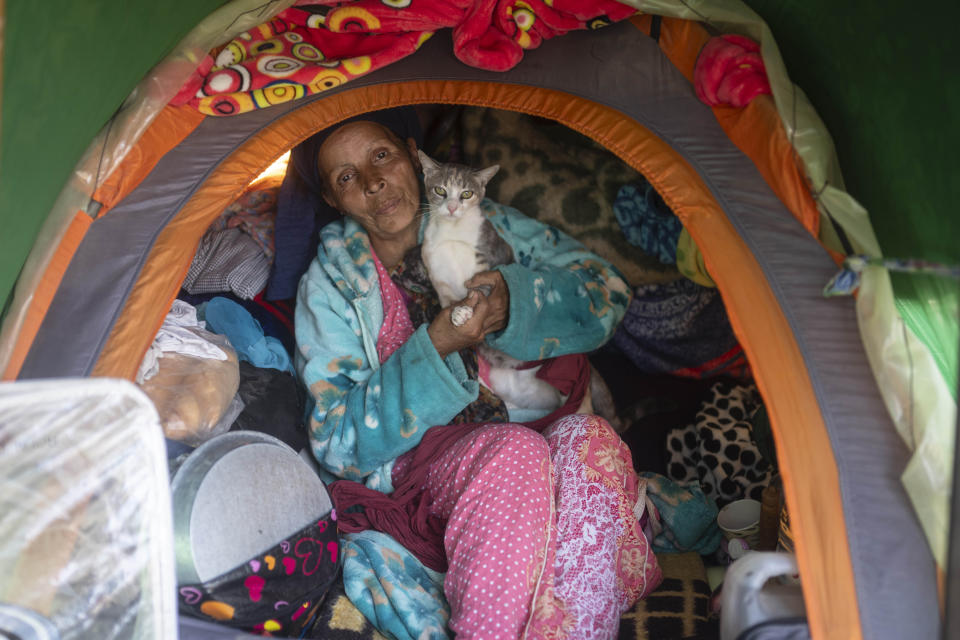 Aisha and her cat Farra who were displaced by the earthquake pose for a portrait inside their tent in Moulay Ibrahim, outside Marrakech, Saturday, Oct. 7, 2023. Villagers in hard-hit regions say one month after the earthquake that they feel frustrated at a lack of details regarding short-term and long-term plans to rehouse them. (AP Photo/Mosa'ab Elshamy)