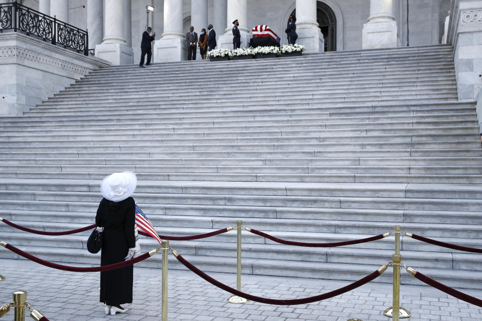 Mary Clement of Silver Spring, Md., holds an American flag as she views the flag-draped casket of Rep. John Lewis, D-Ga., as he lies in state on the East Front Steps of the Capitol in Washington, Monday, July 27, 2020. (AP Photo/Patrick Semansky)