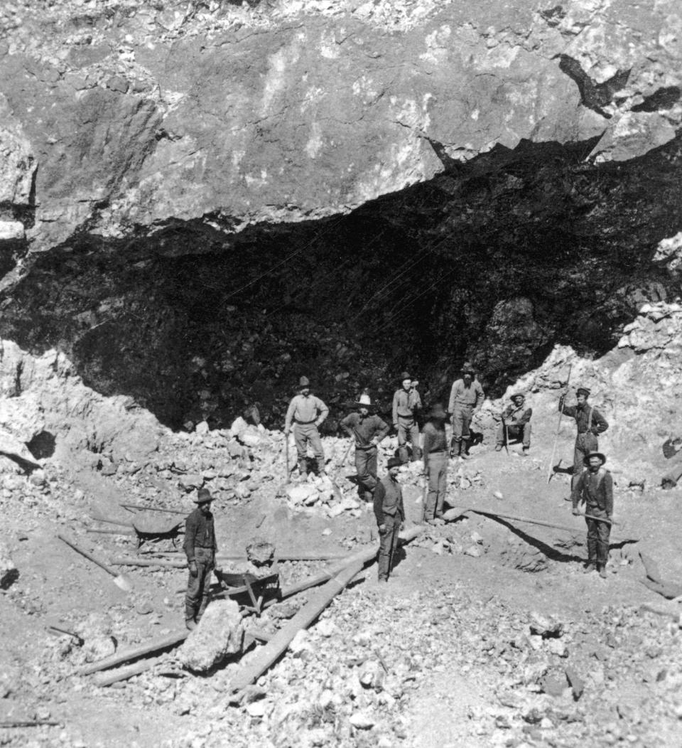 Miners with tools standing in front of the Racine Boy Mine, Silver Cliff, Colorado. (Poor Man and Caribou mines not pictured.)