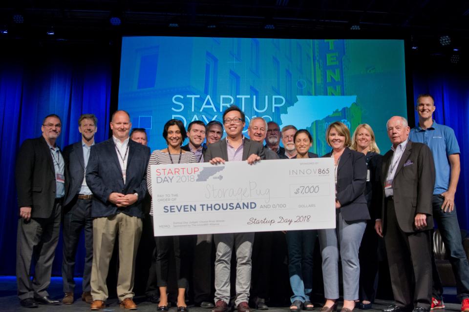 Tommy Nguyen, co-founder and CEO of StoragePug storage facility software company, is presented a $7,000 check at Innov865's Startup Day pitch competition for winning the Judges Choice award. Nguyen also won the $3,000 crowd favorite prize.