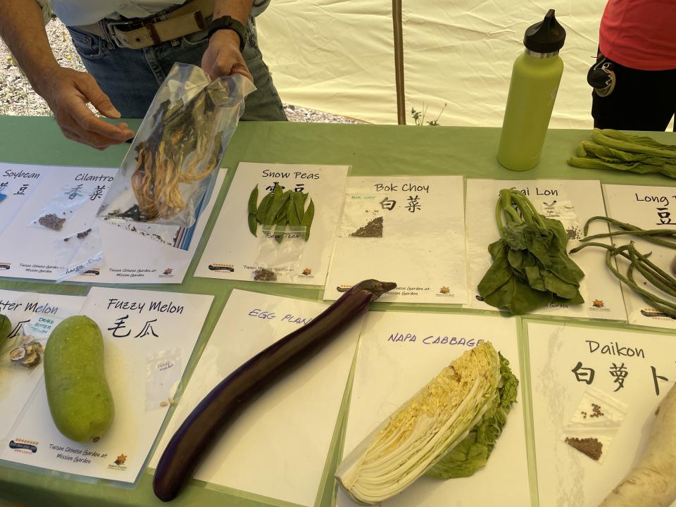 Fe Tom holds a bag of dried bok choi and talks to event attendees about heirloom Chinese foods at the Mission Garden seed swap, on May 27, 2023.