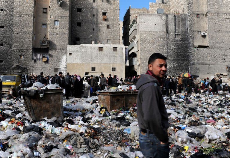 Syrian people are pictured in a bazaar next to a garbage heap in the northern city of Aleppo, on February 14, 2013. Syria's rebels captured a military airbase in the northern province of Aleppo and geared for a major battle against loyalist forces for control of two nearby strategic airports