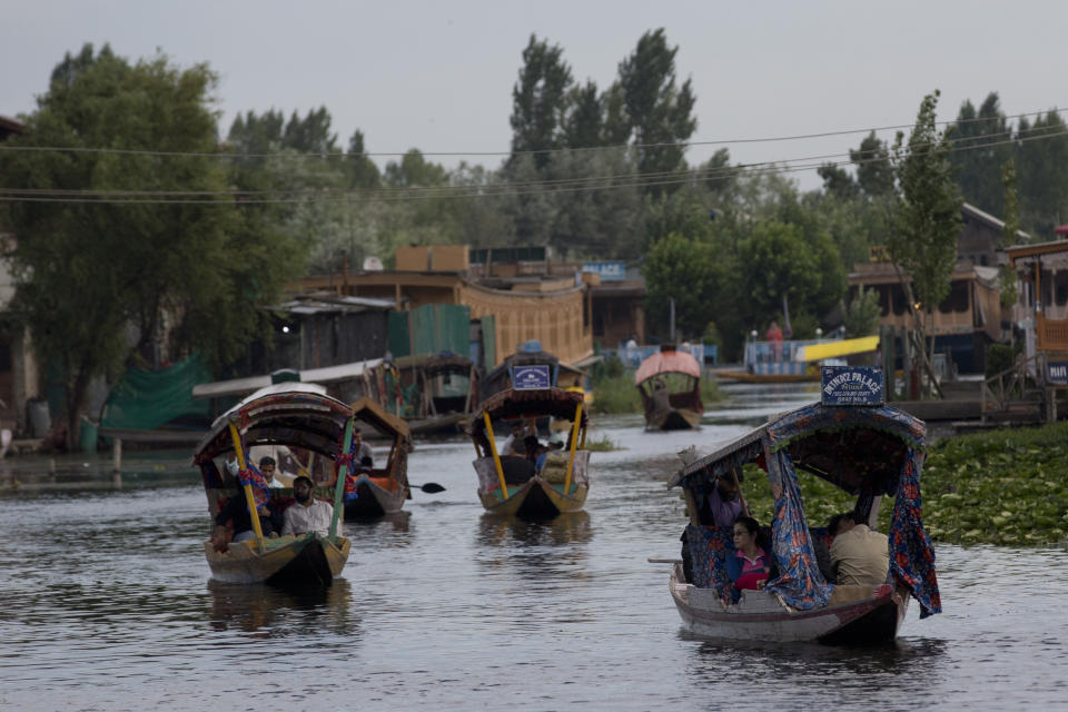 FILE - In this Saturday, Aug. 3, 2019, file photo, Tourists in Shikaras, a traditional gondola, cross the Dal Lake as they prepare to leave Srinagar, Indian controlled Kashmir. Authorities in Indian-controlled Kashmir are allowing tourists back into the region two months after ordering them to leave, citing security concerns. The local government had instructed tourists and Hindu pilgrims to leave on Aug. 2, three days before India stripped the Muslim-majority region of its statehood and special semi-autonomous status. (AP Photo/Dar Yasin, File)