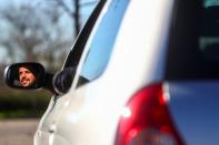 Cristian Lopez poses with his newly-bought 15-year-old second hand car in an empty parking lot in Madrid