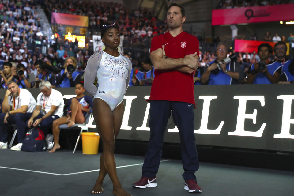 Simone Biles of the U.S. and her coach Laurent Landi wait at the floor during the women's all-around final at the Gymnastics World Championships in Stuttgart, Germany, Thursday, Oct. 10, 2019. (AP Photo/Matthias Schrader)