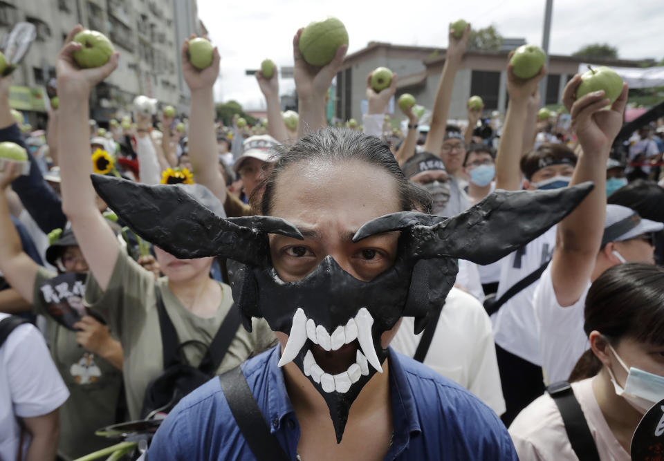 A supporter of opposition Taiwan People's Party (TPP) wears a devil mask as other supporters hold guavas, symbolizing dishonored ballots, during a march to protest against Lai Ching-te's ruling Democratic Progressive party, a day before his presidential inauguration in Taipei, Taiwan, Sunday, May 19, 2024. TPP demands that Lai''s government must implement parliamentary, judicial and constitutional reforms. (AP Photo/Chiang Ying-ying)