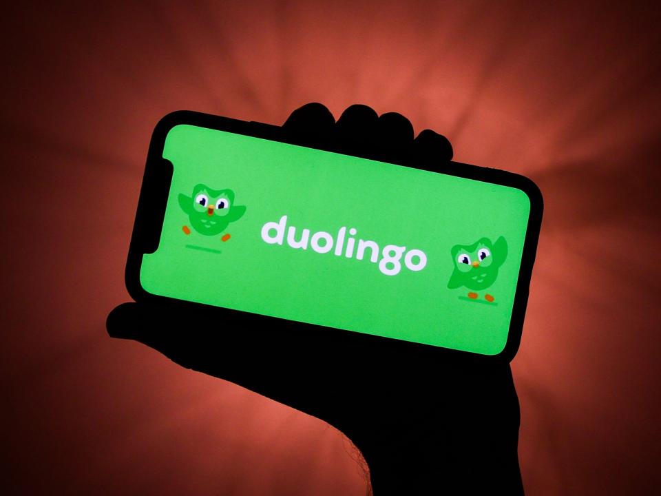 Hand holding phone with Duolingo home screen.