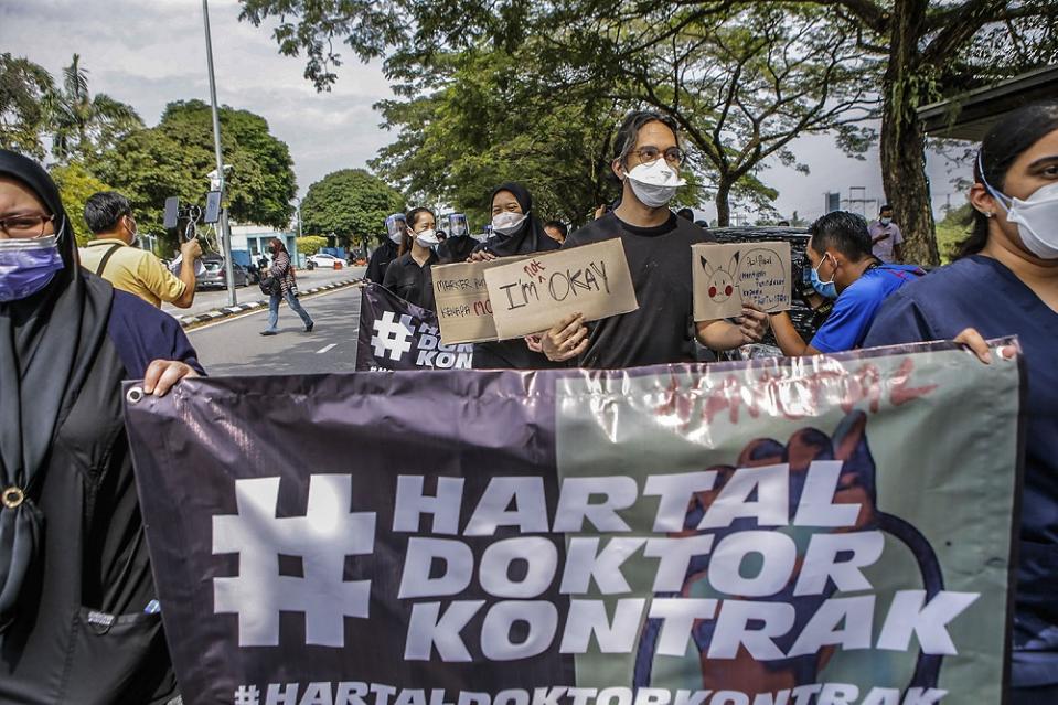 Contract doctors hold aloft placards demanding equal treatment as they go on strike at the Sungai Buloh Hospital July 26, 2021. — Picture by Hari Anggara