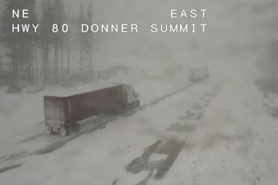 In this image taken from video from a Caltrans remote video traffic camera, a pair of trucks make their way through the snowy conditions along Interstate 80 at Donner Summit, California, on Dec. 1, 2022, in the Sierra Nevada mountains.  / Credit: Caltrans via AP