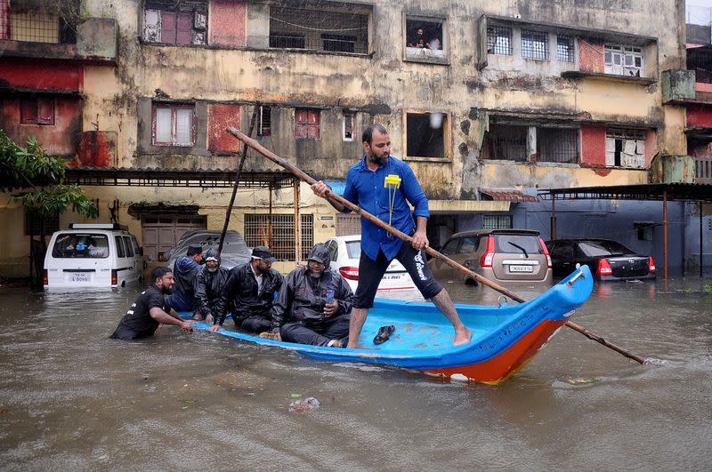 FOTO DE ARCHIVO: Un grupo de personas se desplaza en una barca junto a vehículos parcialmente sumergidos en una zona residencial tras las fuertes lluvias que precedieron al ciclón Michaung en Chennai