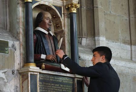 Christian Van Nieuwerburgh places a symbolic quill in the hand of a statue of William Shakespeare, marking the 450th anniversary of his birth inside Holy Trinity Church in Stratford-upon-Avon, in this file photo taken April 26, 2014. REUTERS/Suzanne Plunkett/Files