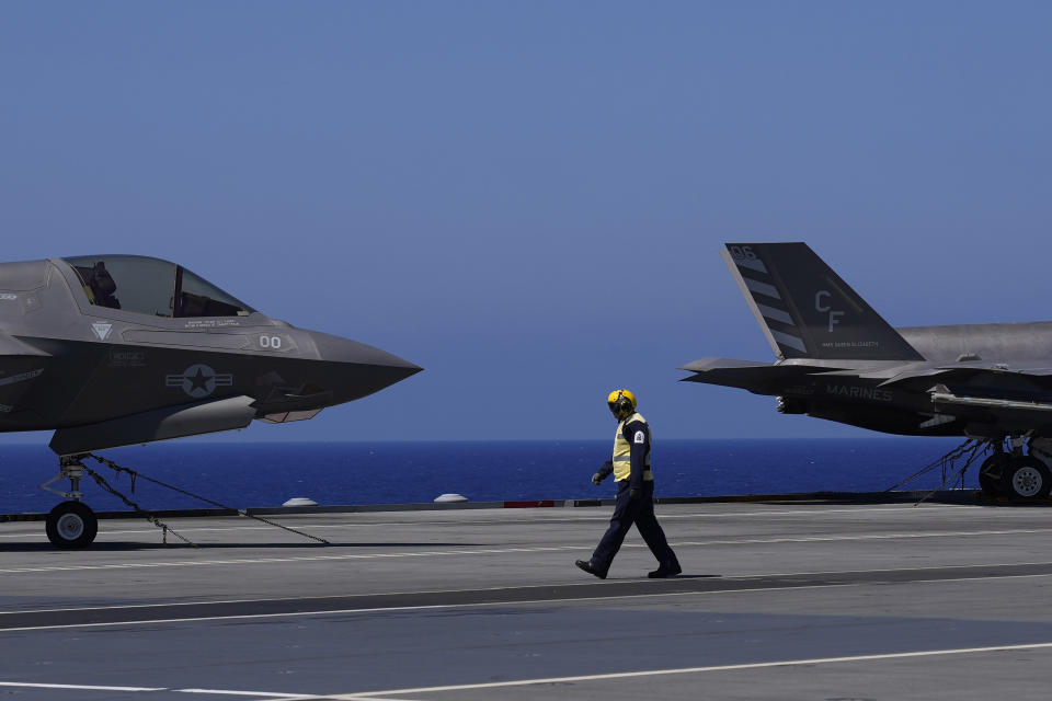 A crew member walks by the F-35 aircrafts for on the U.K.'s aircraft carrier HMS Queen Elizabeth in the Mediterranean Sea on Sunday, June 20, 2021. The British Royal Navy commanders say the U.K.'s newest aircraft carrier HMS Queen Elizabeth is helping to take on the "lion's share" of operations against the Islamic State group in Iraq as Russian warplanes get an up-close look at the cutting-edge F-35 jet in a "cat-and-mouse" game with British and U.S. pilots. (AP Photo/Petros Karadjias)