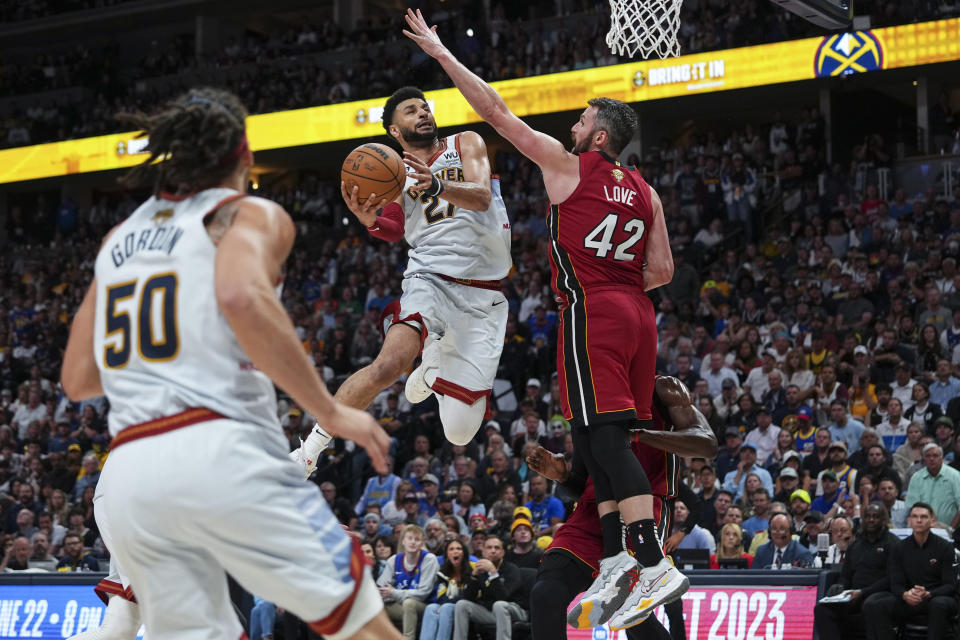 Denver Nuggets guard Jamal Murray, center, shoots while defended by Miami Heat forward Kevin Love, right, during the second half of Game 5 of basketball's NBA Finals, Monday, June 12, 2023, in Denver. (AP Photo/Jack Dempsey)