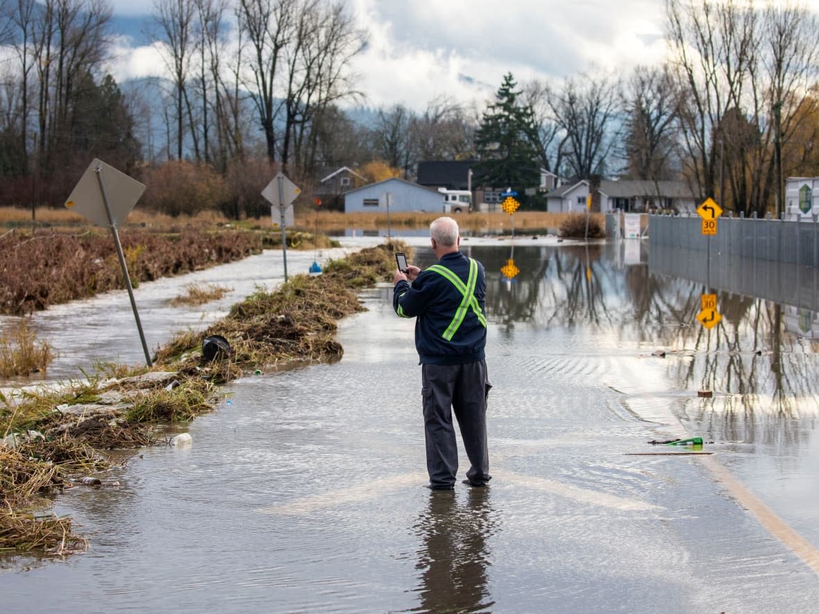 A contractor walks along a flooded road in the neighbourhood of Huntingdon in the Sumas Prairie flood zone in Abbotsford, B.C.  (Ben Nelms/CBC - image credit)