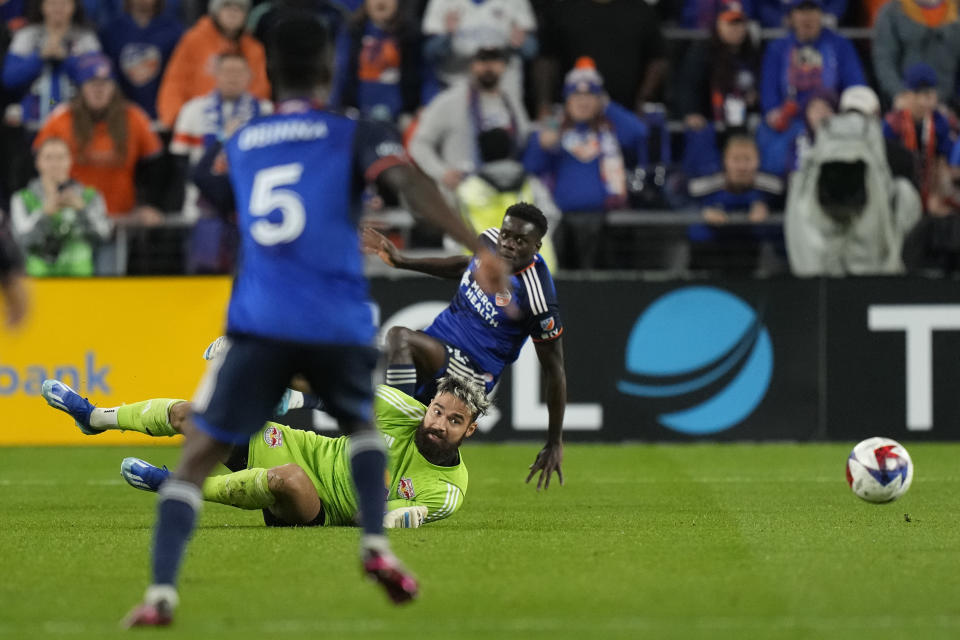 New York Red Bulls goalkeeper Carlos Miguel Coronel (1) clears the ball from FC Cincinnati forward Dominique Badji (14), leaving the goal open, as FC Cincinnati midfielder Obinna Nwobodo (5) moves in during the first half of an MLS playoff soccer match, in Cincinnati, Sunday, Oct. 29, 2023. (AP Photo/Carolyn Kaster)