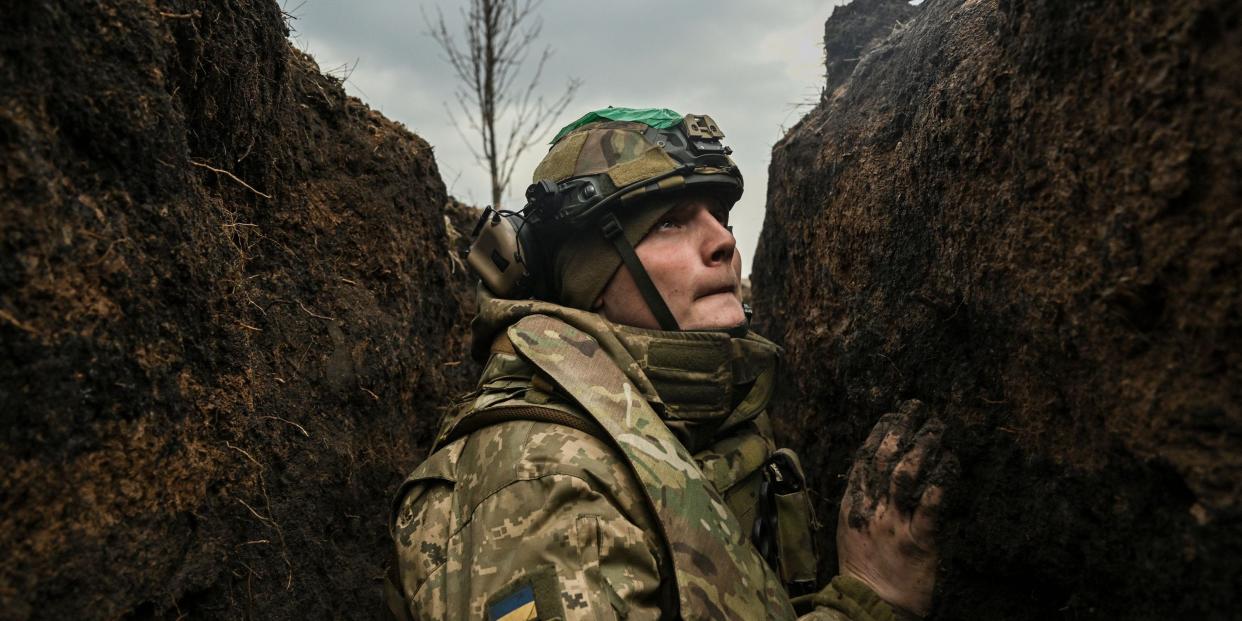 A Ukrainian serviceman takes cover in a trench during shelling next to a 105mm howitzer near the city of Bakhmut, on March 8, 2023.