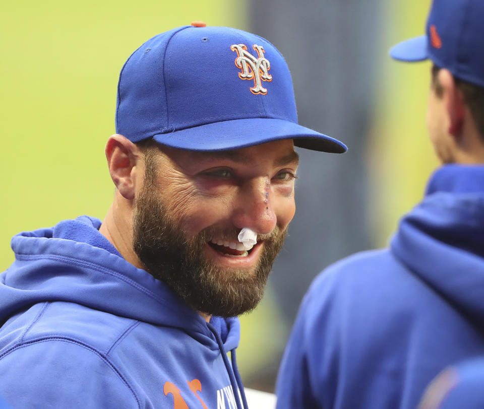 New York Mets Kevin Pillar smiles in the dugout during the team's baseball game against the Atlanta Braves on Tuesday, May 18, 2021, in Atlanta. Pillar suffered multiple nasal fractures when he was hit on the face by a fastball from Braves reliever Jacob Webb on Monday. Pillar met Tuesday with a facial specialist in Atlanta to determine the next steps. He was placed on the 10-day injured list, but was at Truist Park to watch the second game of the series between the NL East rivals. (Curtis Compton/Atlanta Journal-Constitution via AP)