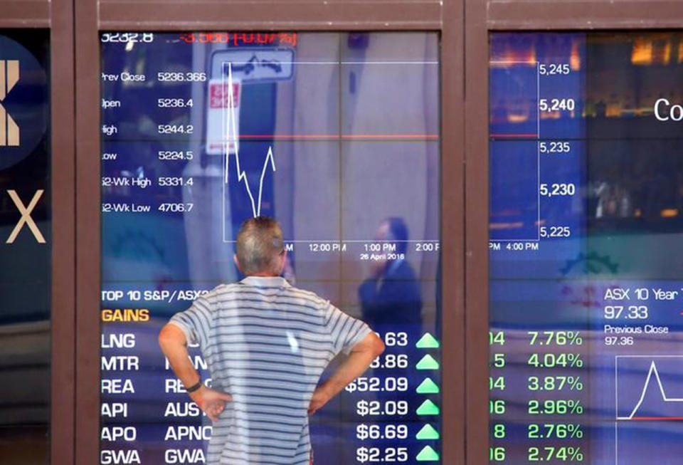 A man reacts as he looks at a board displaying stock prices at the Australian Securities Exchange (ASX) in Sydney, Australia, April 26, 2016. REUTERS/David Gray