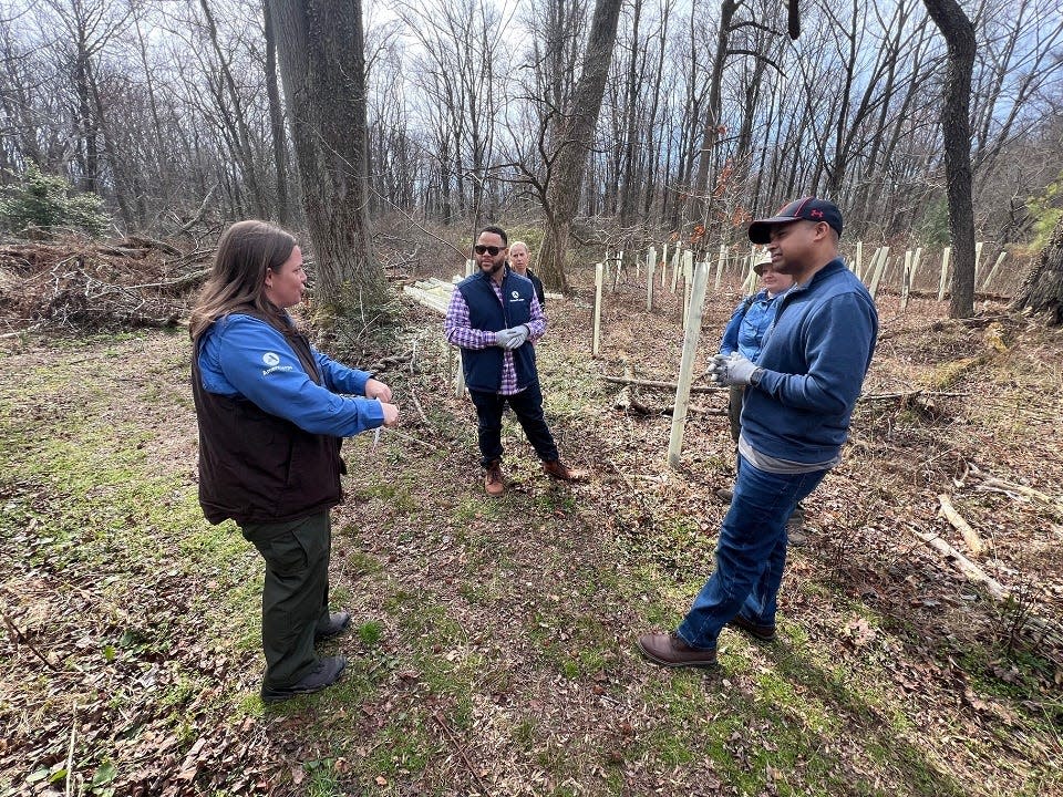 At left, Maryland Conservation Corps Director Sara Marcinak speaks to AmeriCorps CEO Michael Smith, center, and Maryland Service and Civic Innovation Secretary Paul Monteiro, at right, at the Corcoran Environmental Study Area in Annapolis on March 12, 2024.