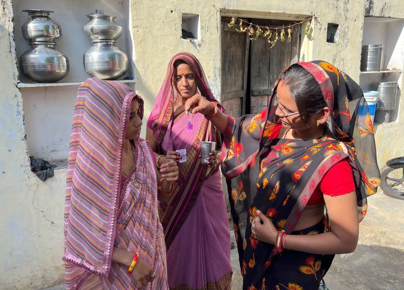 Members of Village Water and Sanitation Committee conduct a test on a water sample inside a house in Manda Bhopawas village