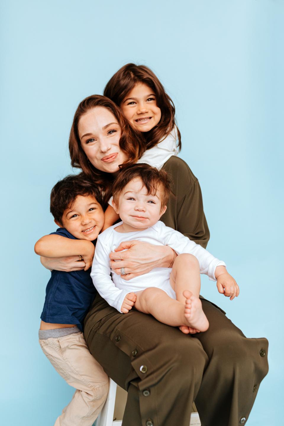 Laura Modi, co-founder of the infant formula start-up Bobbie poses on a chair with her three young children.