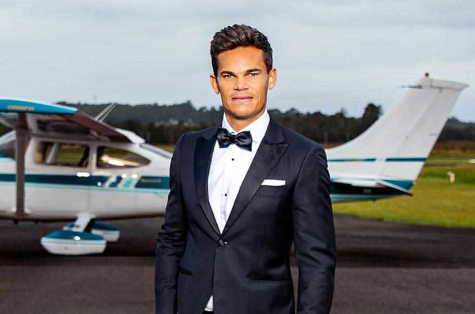 The Bachelor Australia 2021 Jimmy Nicholson wearing a tuxedo in front of a light aircraft. Photo: Channel 10.