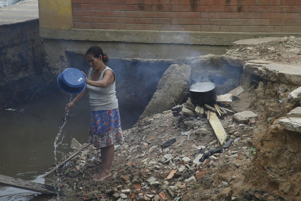 An Indigenous woman from the Kanamari ethnic group washes a cooking pot on the Atalaia do Norte river shore, in Amazonas state, Brazil, Sunday, June 12, 2022. Federal Police and military forces are carrying out searches and investigations into the disappearance of British journalist Dom Phillips and Indigenous affairs expert Bruno Araujo Pereira in the Javari Valley Indigenous territory, a remote area of the Amazon rainforest in Atalaia do Norte, Amazonas state. (AP Photo/Edmar Barros)